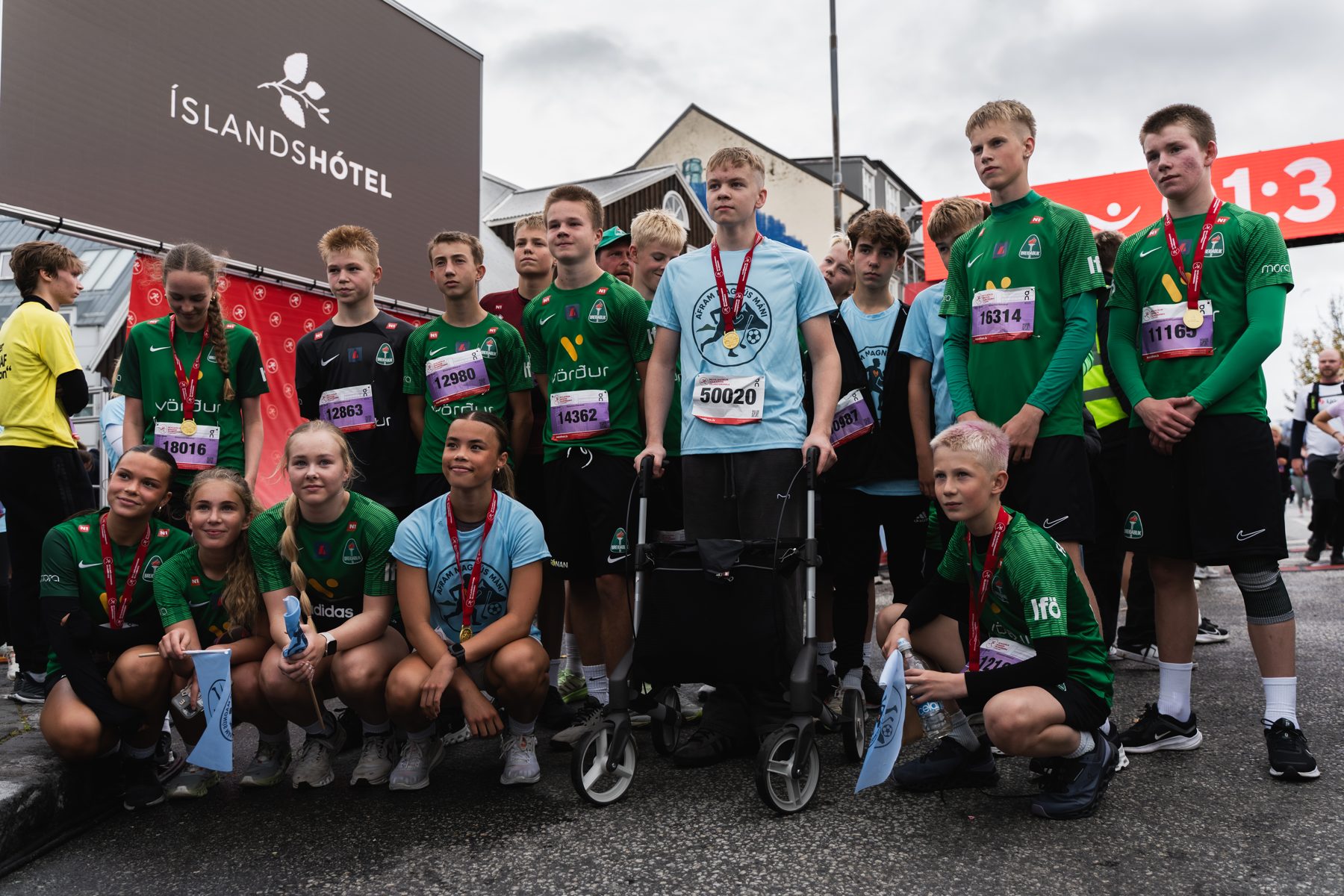 Magnús Máni stendur með göngugrindina sína og medalíu, umkringdur liðsfélögum í Reykjavíkurmaraþoninu